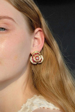 A model wearing ruby floral cluster stud earrings in gold, shown in side profile with soft natural makeup and loose hair.