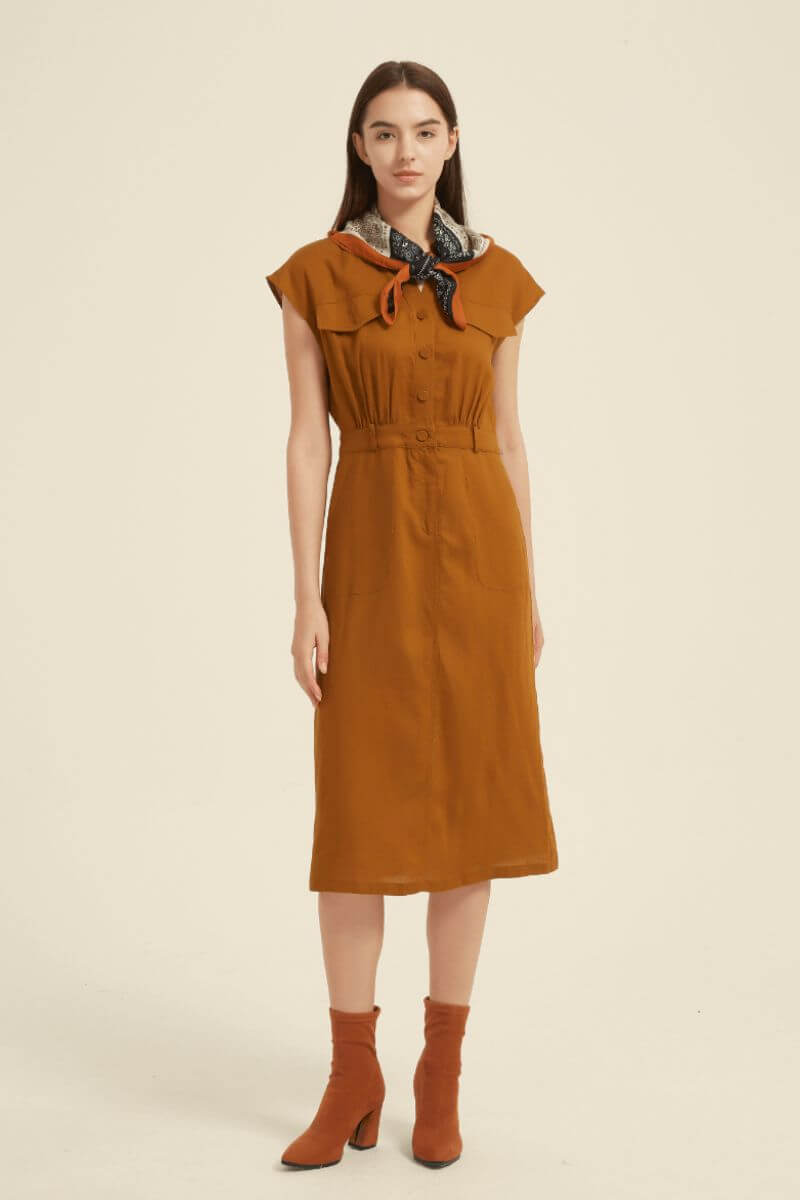 Studio close-up of a rust midi shirt dress featuring cap sleeves, front buttons, and a defined waistline — elegant minimalist design in warm autumn tones.
