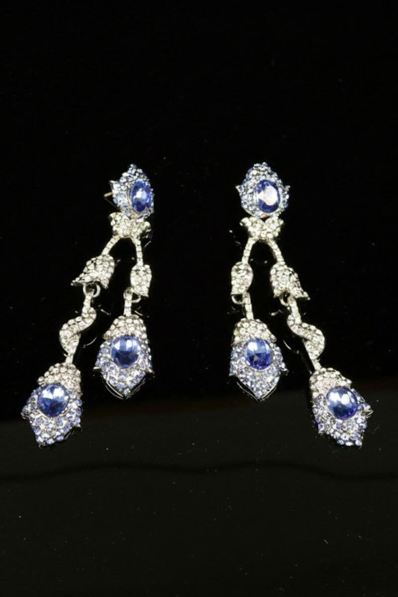 Articulated drop earrings showcasing multiple sapphire-blue stones set in a vintage-inspired silver-tone frame, designed to sway softly with each movement.