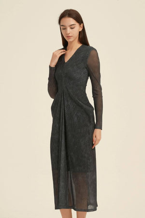 Angled view of a black midi dress showing the V-neck bodice, sheer long sleeves, draped front pleat, and calf-length semi-sheer skirt.