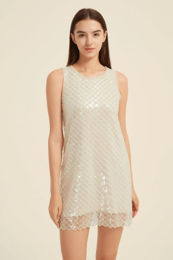 Model wearing a sleeveless champagne sequin mini dress with round neckline and shimmering geometric beaded pattern.