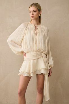 A close view of the soft pearl pleated chiffon mini dress set showing the delicate pleats, tie-neckline, cinched waist, and layered skirt texture.