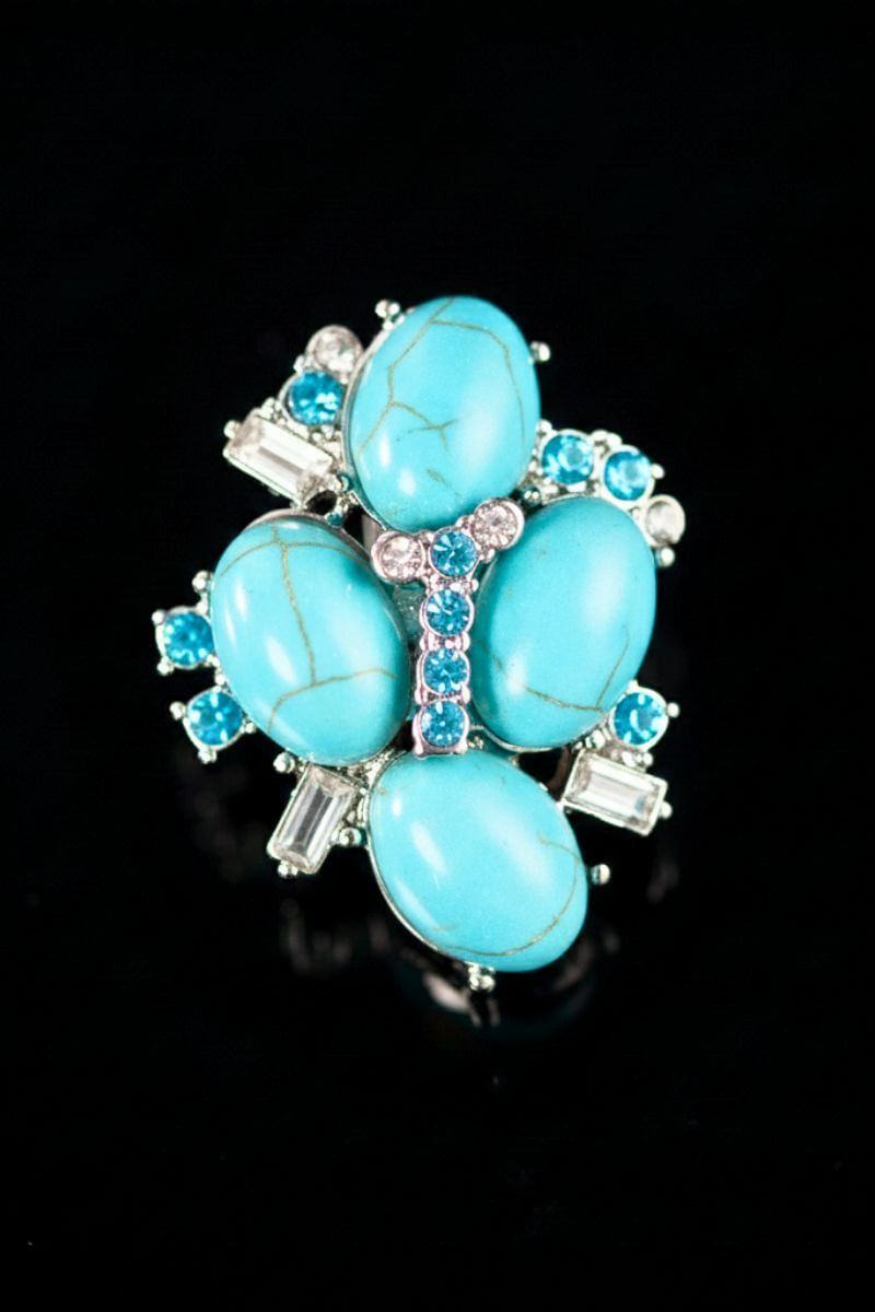 A close-up front view of a turquoise cluster stud earring featuring oval turquoise stones arranged in a floral shape with clear crystal accents on a black background.
