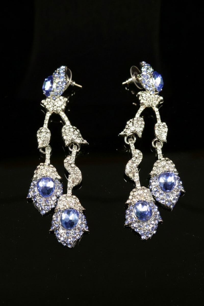 Statement earrings with layered blue oval crystals and sparkling clear rhinestones, connected by delicate articulated links for elegant movement.