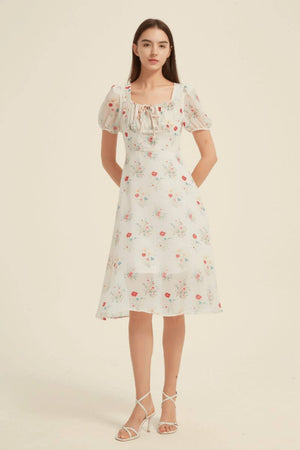 Front view of a white floral midi dress with puff sleeves, ruched square neckline, and feminine silhouette — romantic garden dress from Sioéne.