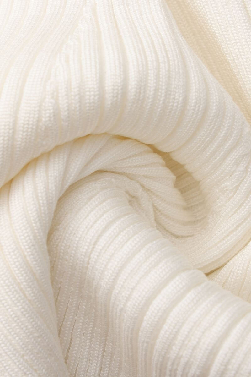 Close-up of soft white ribbed knit fabric showing its textured stretch pattern and smooth woven details.