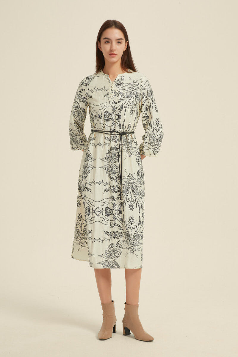Angled front view of a cream midi dress with a detailed black botanical print, loose three-quarter sleeves, and a belted waistline.
