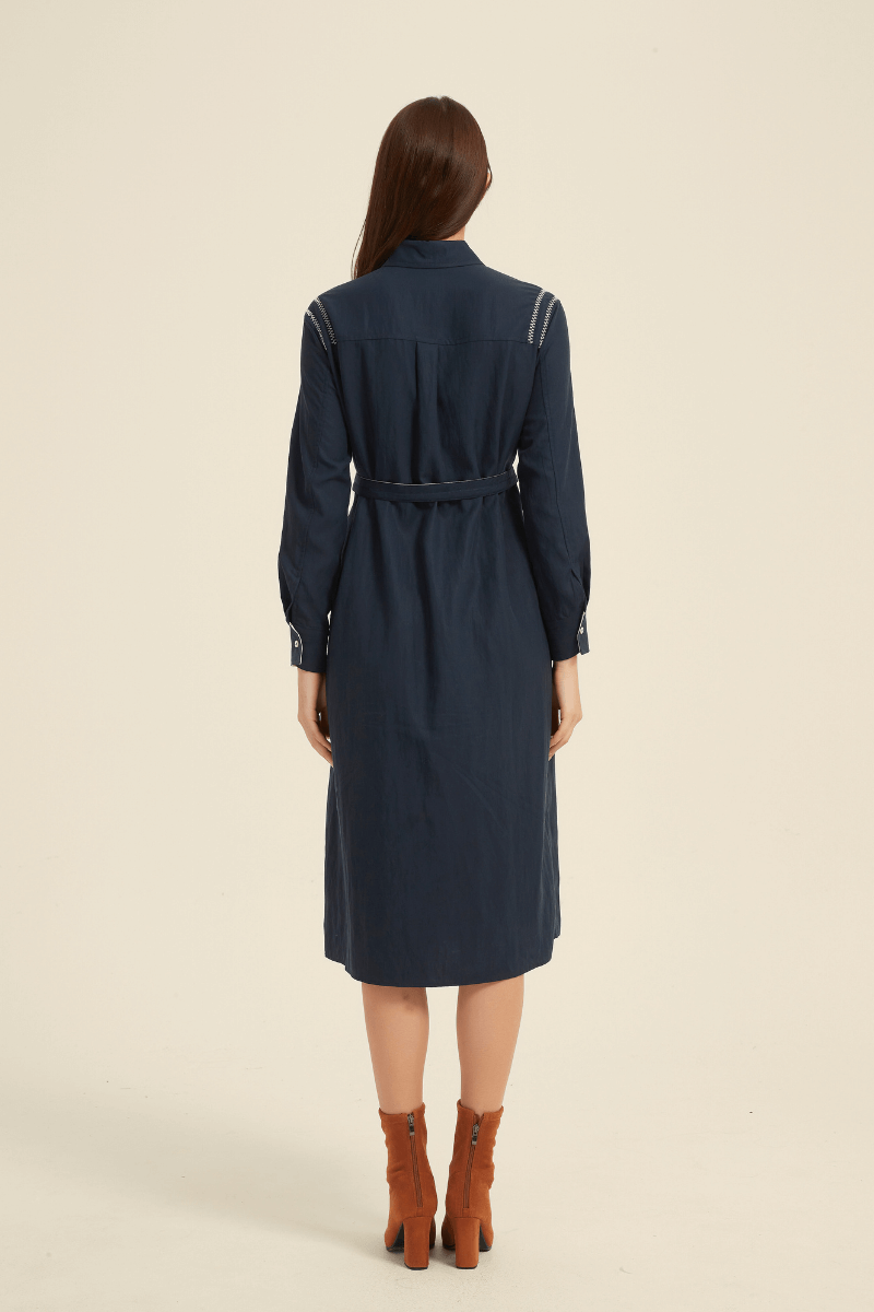 Back view of a navy midi shirt dress featuring a collared neckline, long sleeves, belted waist, and decorative stitching on the shoulders.