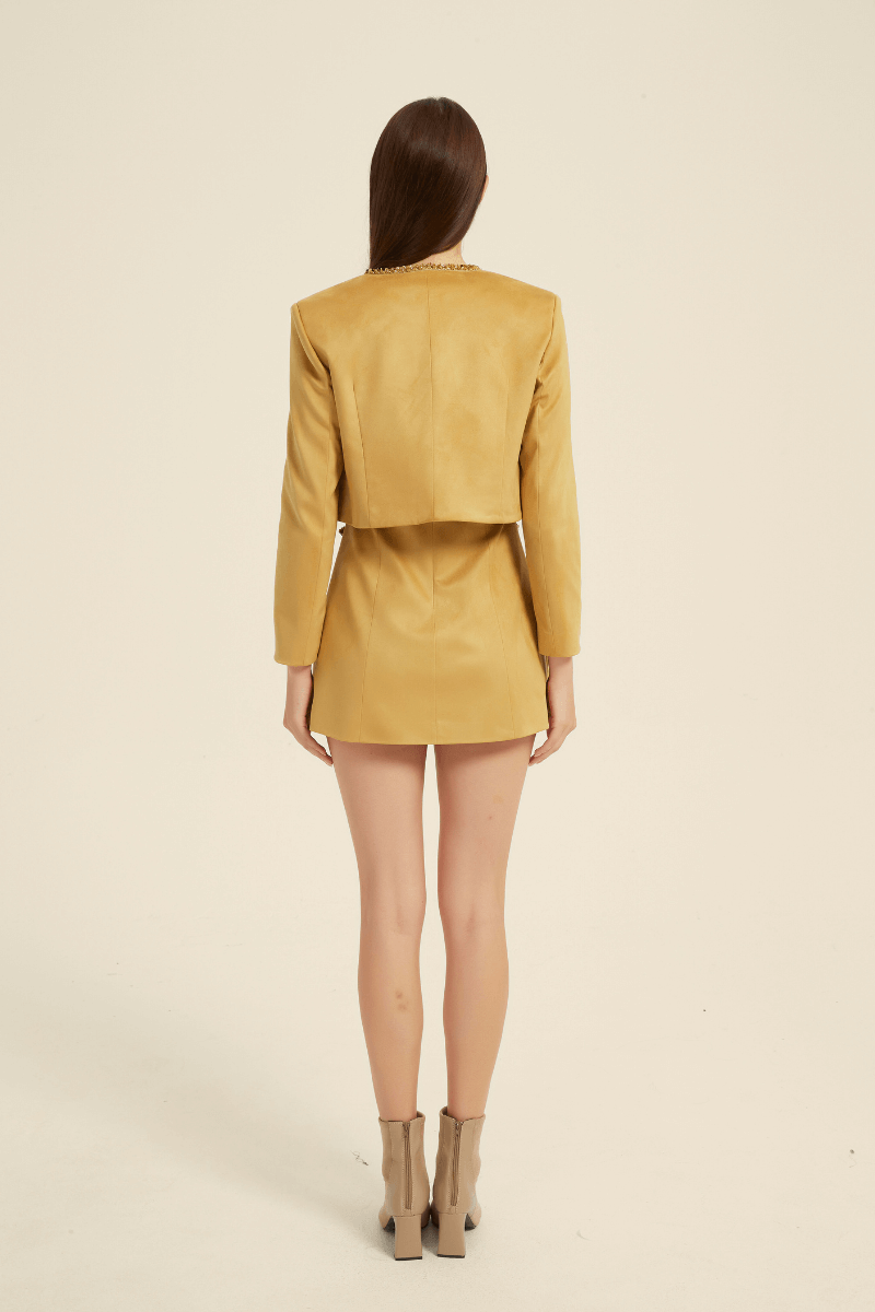 Back view of a yellow two-piece mini dress set featuring a sleeveless dress with a beaded neckline, paired with a cropped long-sleeve jacket and a concealed back zipper.