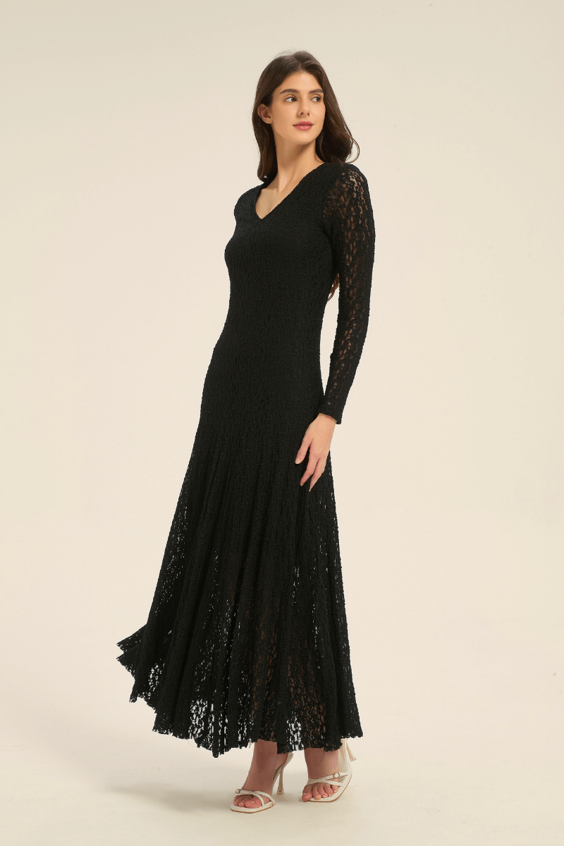 Model wearing black lace long sleeve maxi dress, angled front view highlighting flared skirt and V-neckline.