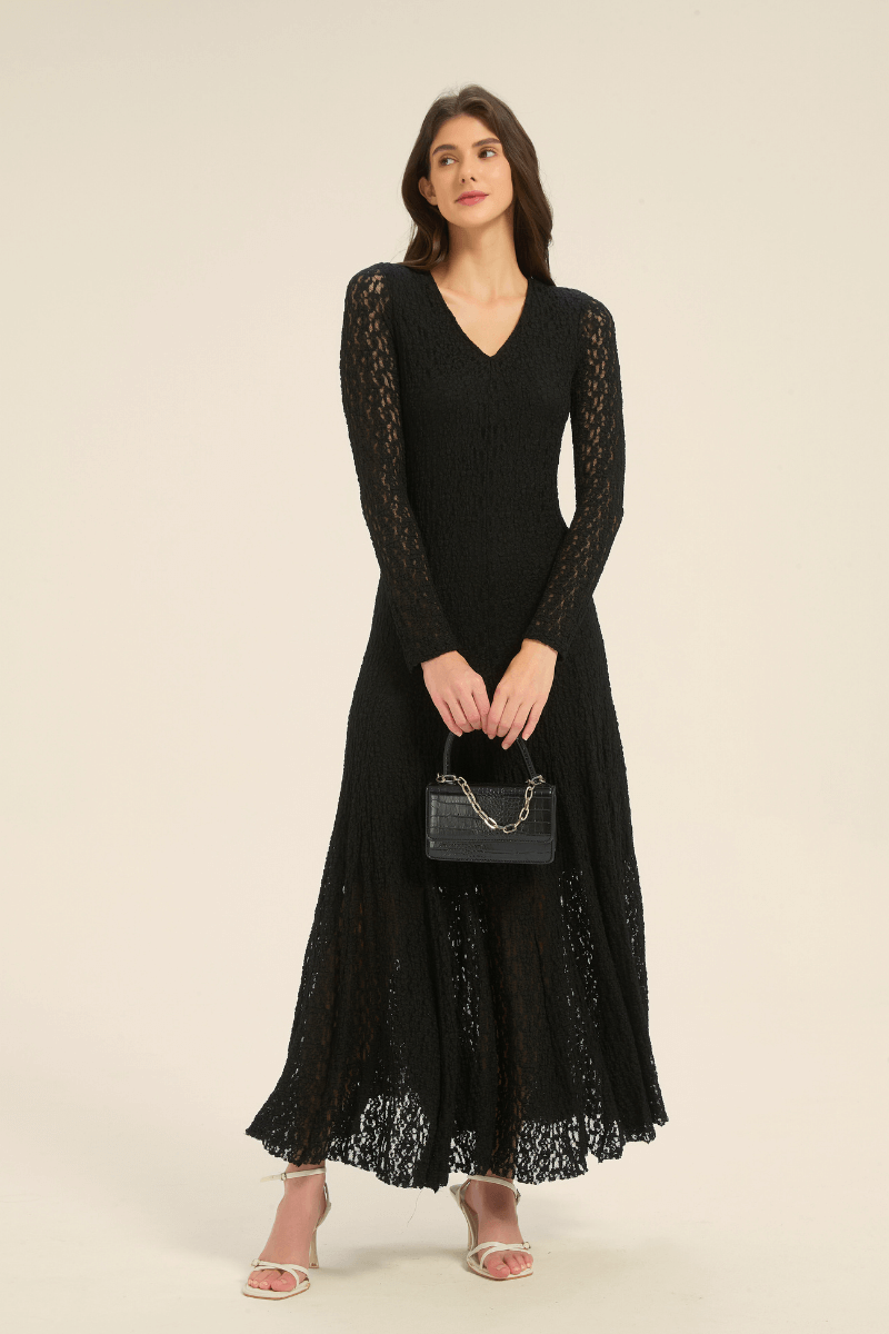 Black lace long sleeve maxi dress styled with a small black handbag and white strappy heels.