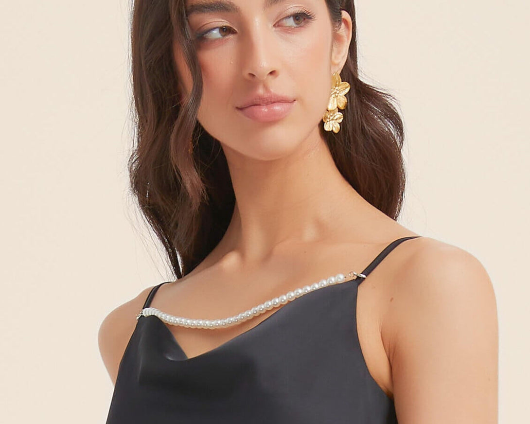 Close-up of black satin dress featuring pearl-trim neckline and thin adjustable straps