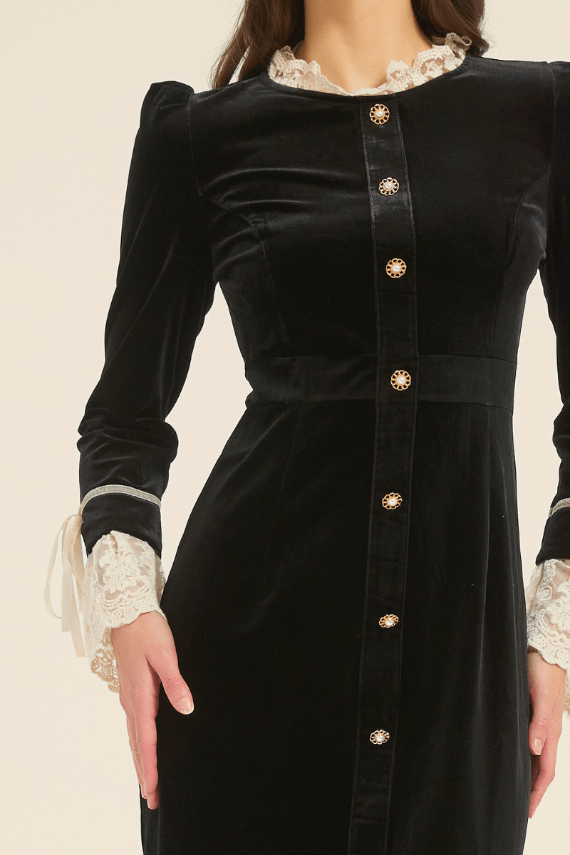 Close-up of black velvet dress bodice with gold pearl buttons and lace-trim cuff accents.
