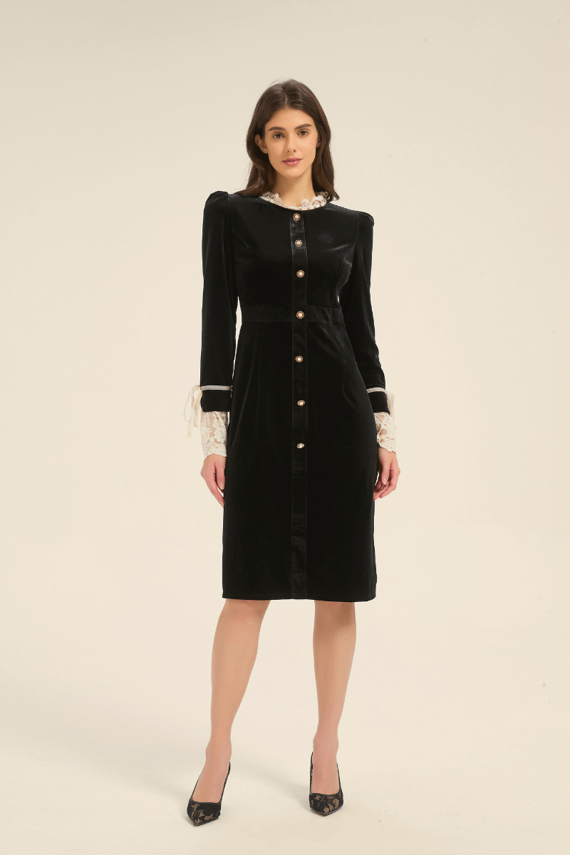 Model wearing a black velvet midi dress with pearl gold buttons and lace-trim cuffs, standing front view.