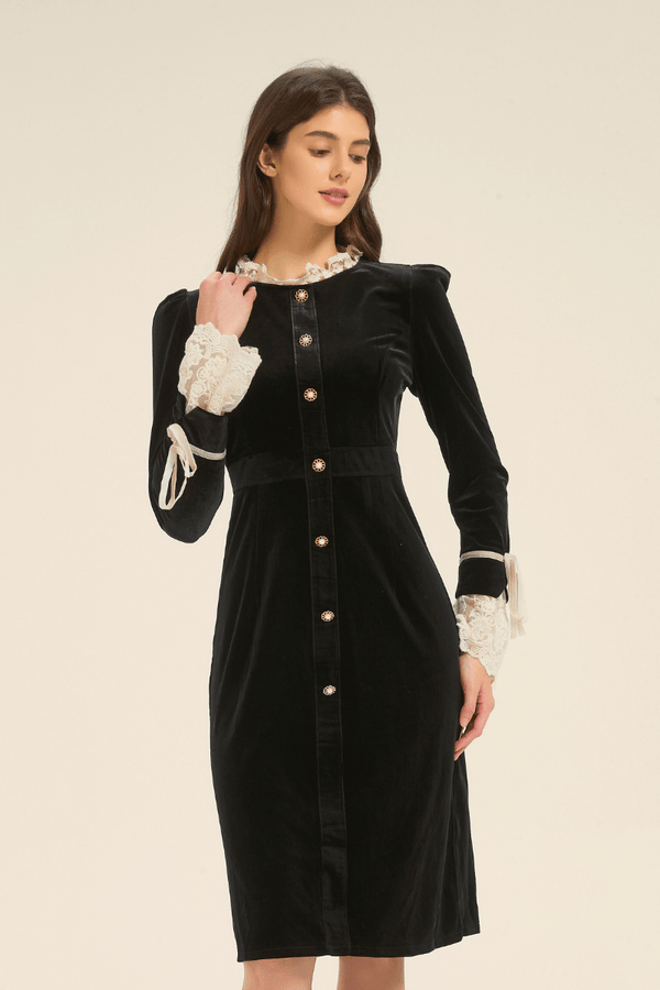 Three-quarter view of a model in a black velvet dress featuring lace-trim cuffs and decorative buttons.