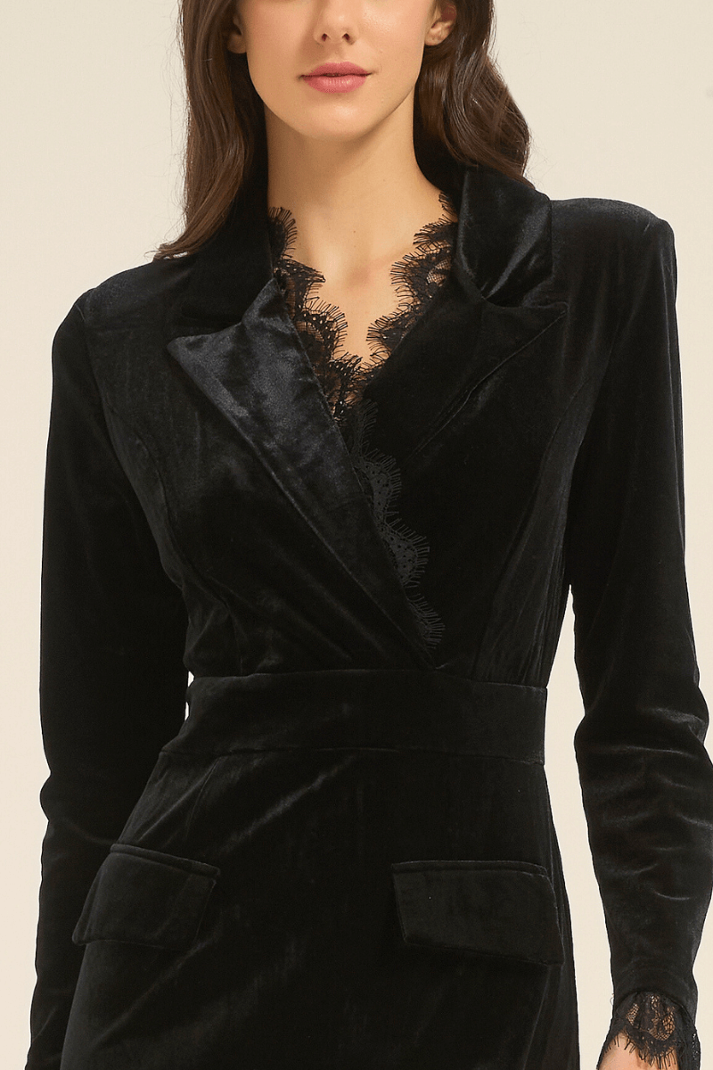 Close-up view of black velvet midi dress featuring notched lapel neckline with delicate lace trim and long sleeves.