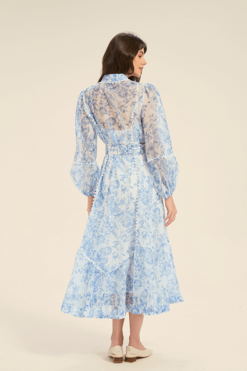 Back view of a blue floral print midi dress with long puff sleeves and belted waist.