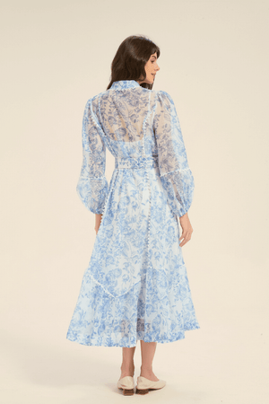 Back view of a blue floral print midi dress with long puff sleeves and belted waist.