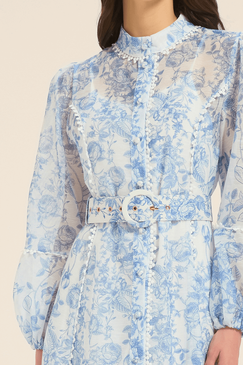 Detailed close-up of the belt and button-down design on a blue floral print midi dress.