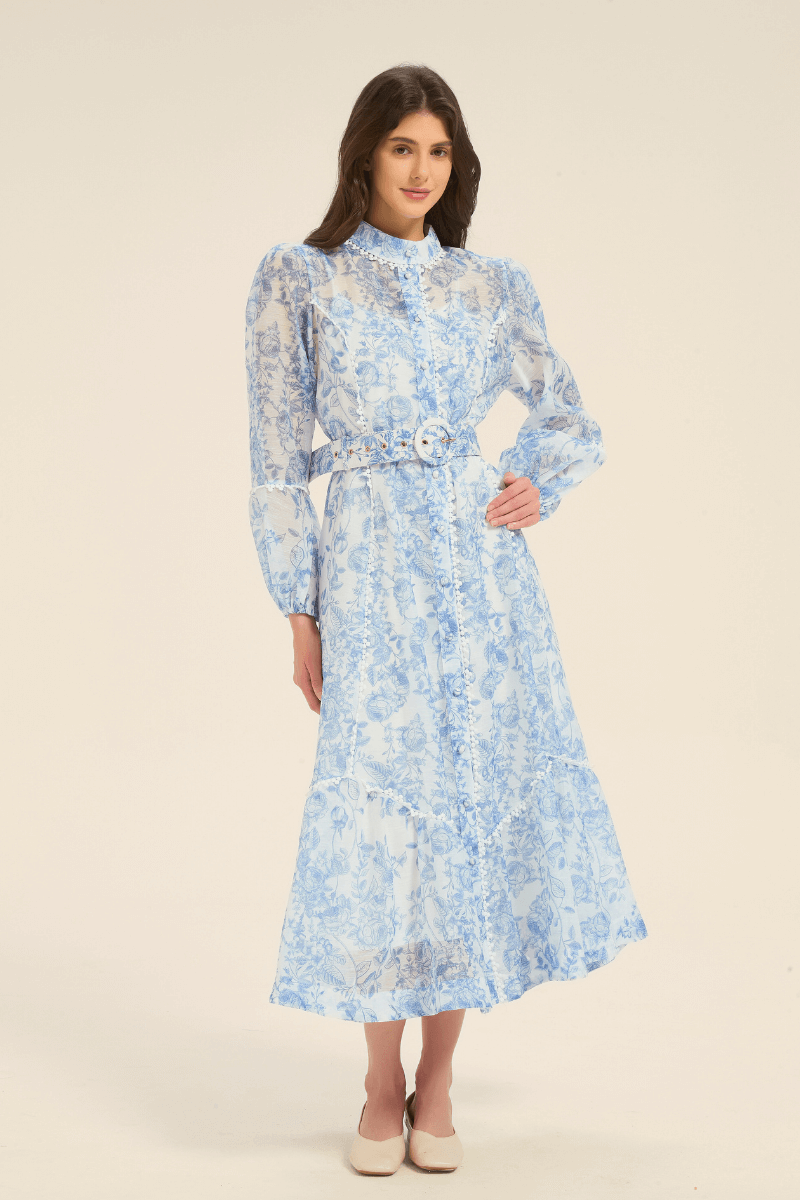 Model wearing a blue floral print midi dress with a belted waist and button-down front.