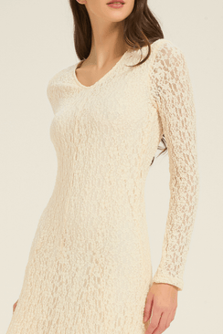 Side view of model in cream lace long-sleeve maxi dress, showing the flared hem and elegant lace details.