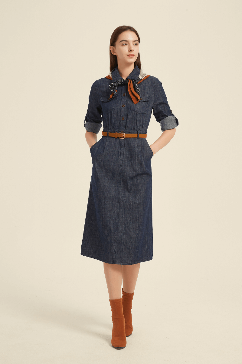 Front view of a denim midi shirt dress featuring a button-down design, chest flap pockets, rolled sleeves, a brown belt, and a printed scarf tied at the neck.