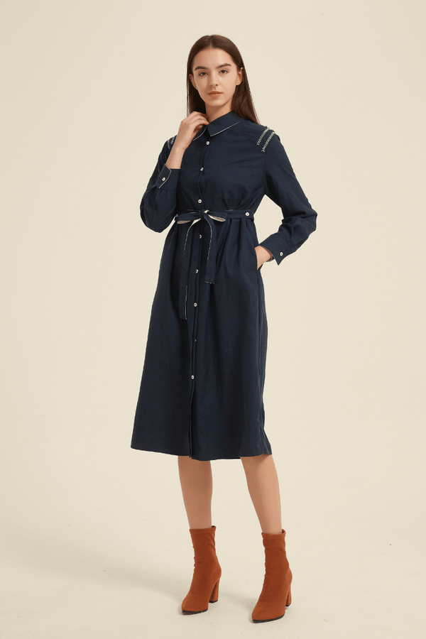 Front view of a navy midi shirt dress featuring a button-down front, collared neckline, belted waist, long sleeves, and decorative stitching at the shoulders.