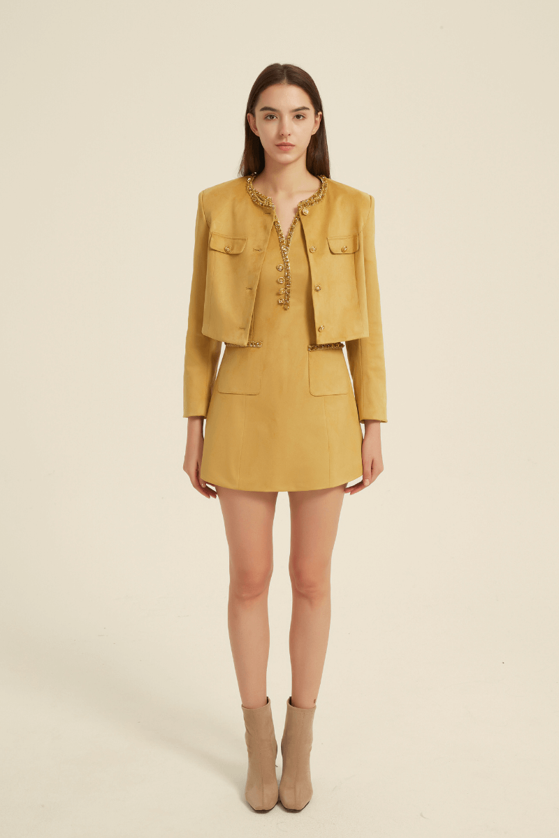 Front view of a yellow two-piece mini dress set featuring a sleeveless dress with a beaded neckline, paired with a cropped long-sleeve jacket with button closure and flap pockets.