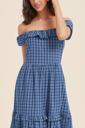 Close-up of a woman wearing a blue gingham off-shoulder maxi dress with ruffle neckline and tiered skirt — breezy and charming for warm days.