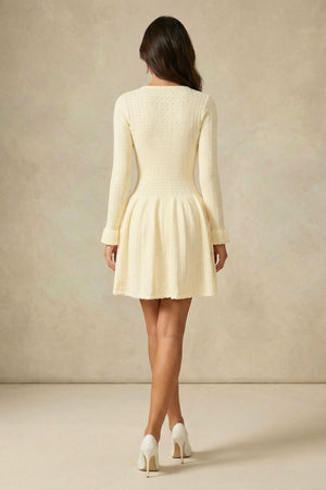 Back view of an ivory long-sleeve knit mini dress showing the fitted waist and softly flared skirt in a clean studio setting.