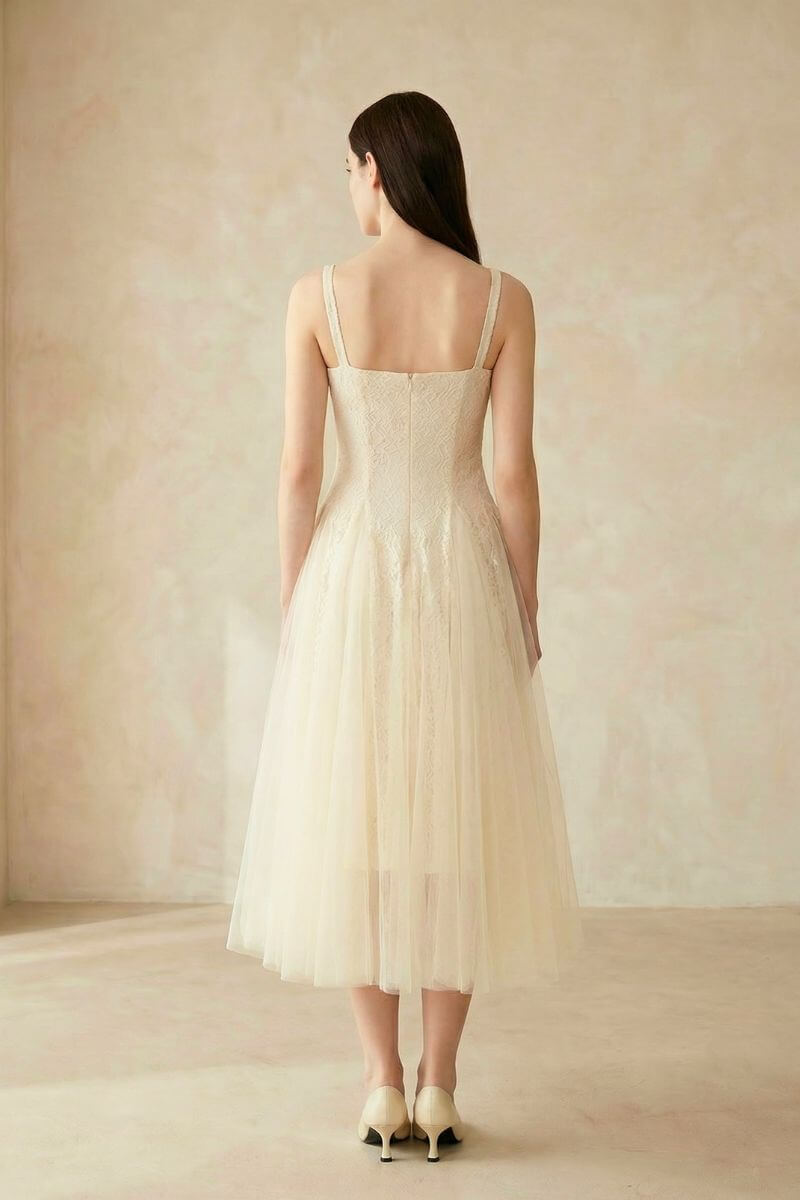 The back view of an ivory lace tulle midi dress with a fitted lace bodice, zipper closure, and soft tulle skirt.