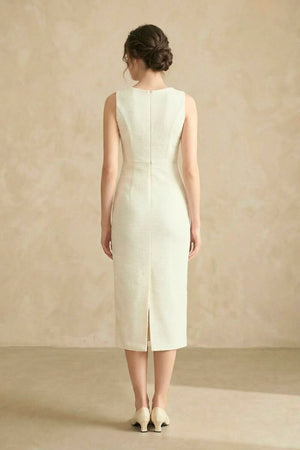 The back view of an ivory tweed midi dress featuring a clean seam line, zipper closure, and back slit.