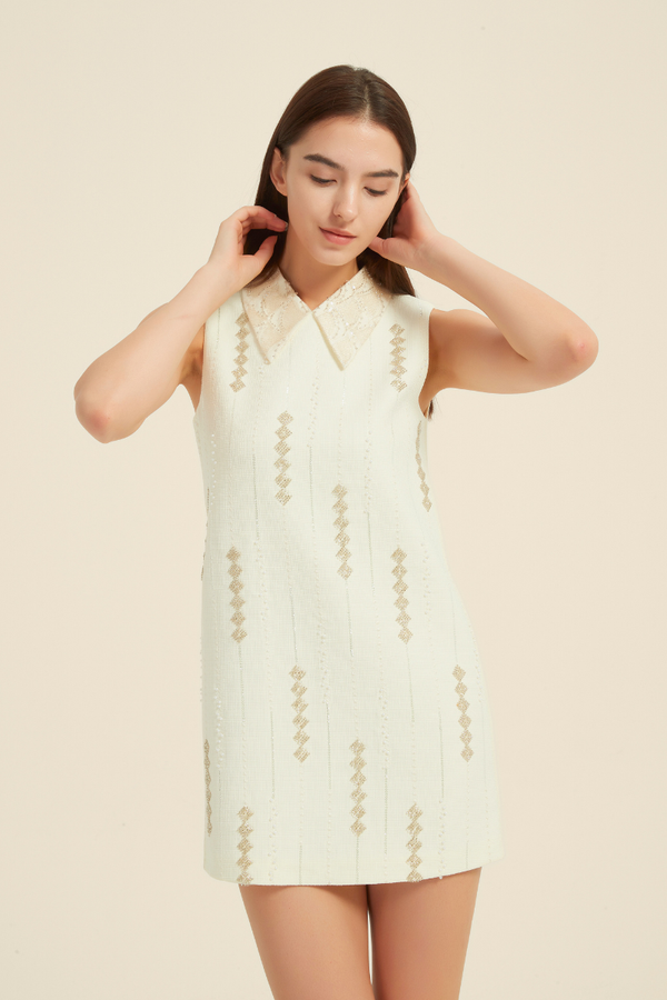 Close-up front view of cream mini dress with sheer lace collar and vertical gold sequin embroidery, styled in a sleeveless A-line silhouette.