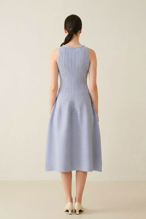Back view of a light blue sleeveless midi dress featuring a ribbed fitted bodice and a softly structured flared skirt in a minimal studio.