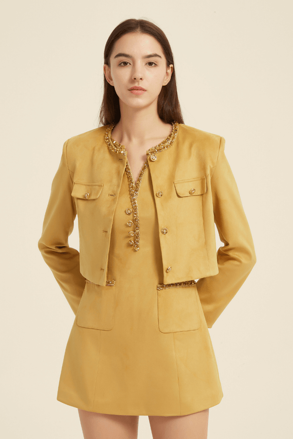 Front view of a mustard yellow two-piece set featuring a sleeveless mini dress with beaded trim neckline and a matching cropped long-sleeve jacket with front flap pockets and decorative buttons.