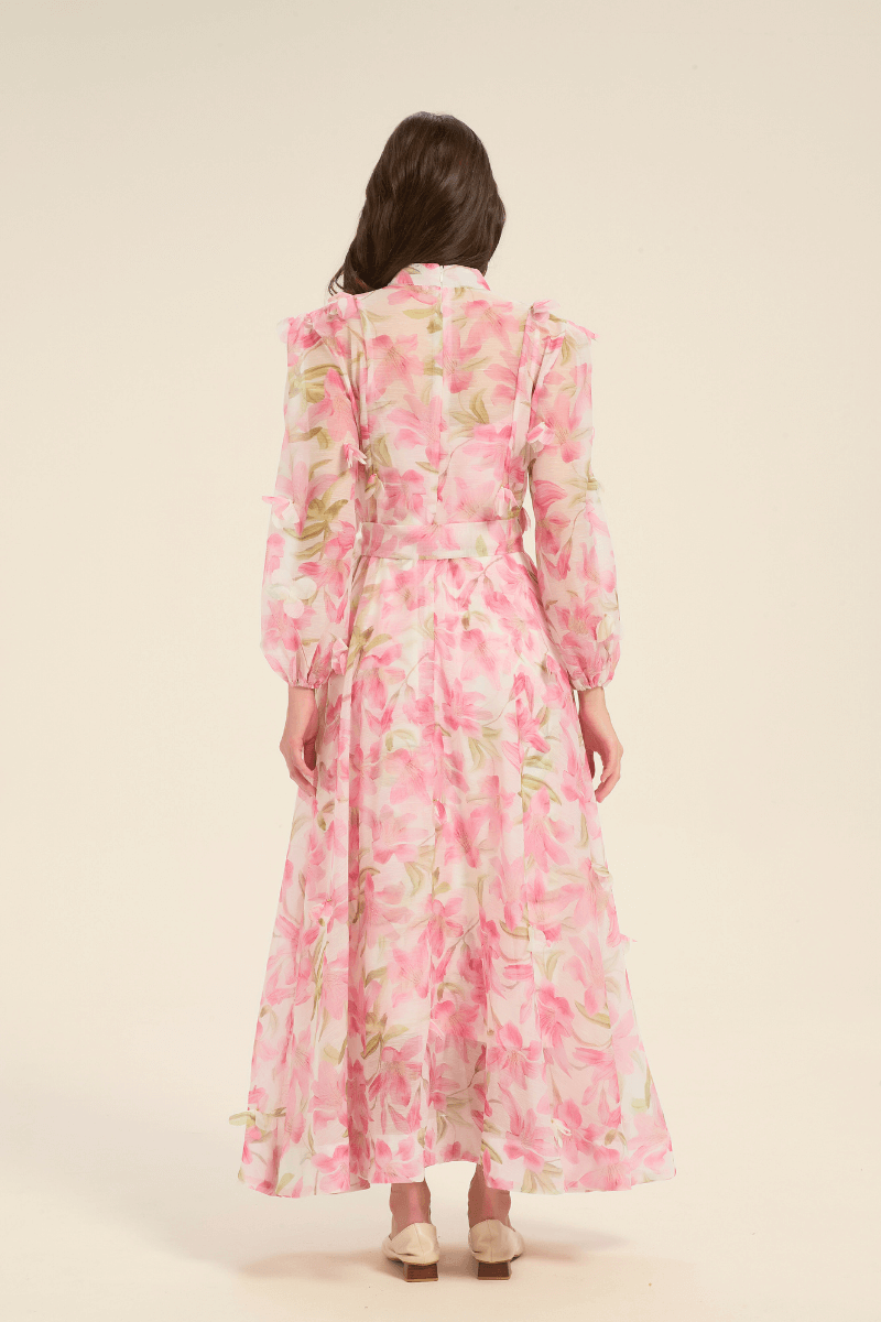 Back view of pink floral maxi dress with soft pleats, waist tie, and full-length flowing skirt.