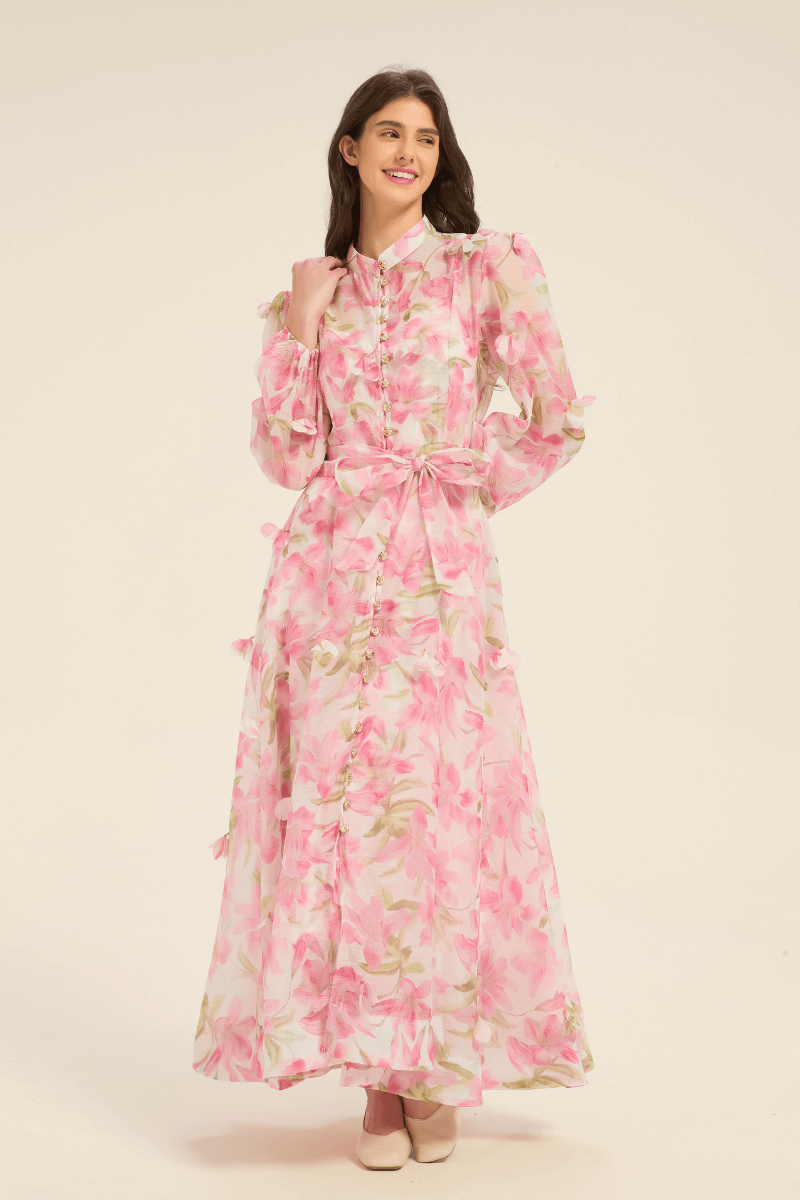 Front view of pink floral maxi dress featuring puff sleeves, pearl button details, and a matching fabric belt.