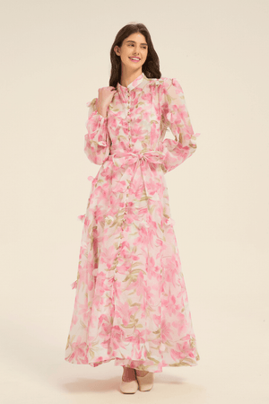 Front view of pink floral maxi dress featuring puff sleeves, pearl button details, and a matching fabric belt.