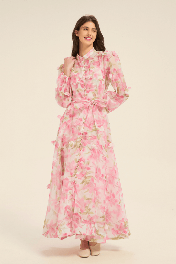 Front view of pink floral maxi dress featuring puff sleeves, pearl button details, and a matching fabric belt.