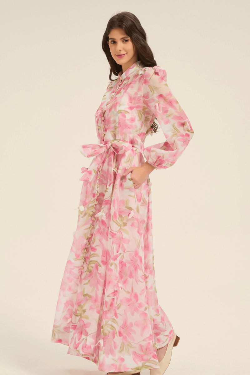 Side view of pink floral maxi dress with puff sleeves, button-down front, and a bow-tied belt at the waist.