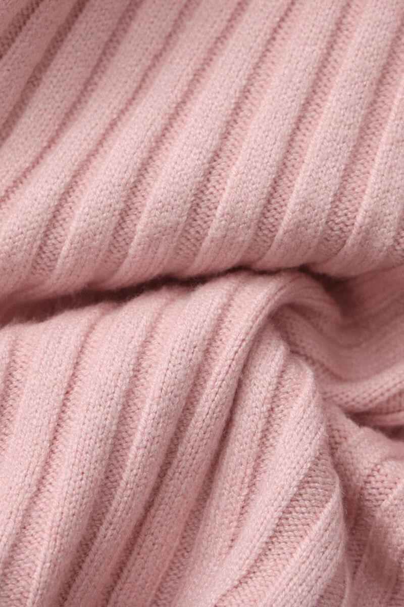 Close-up of a soft pink ribbed knit sweater fabric showing its cozy texture and fine stitching, highlighting the material used for Sioéne’s ruffled pink knit top.