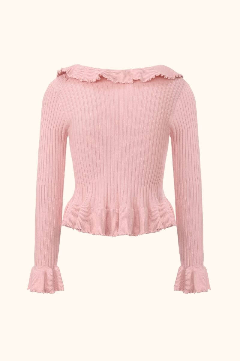 Back view of a pink ribbed knit sweater with subtle ruffle trim along the neckline and hem, showing the fitted shape and long sleeve design in Sioéne’s knitwear line.