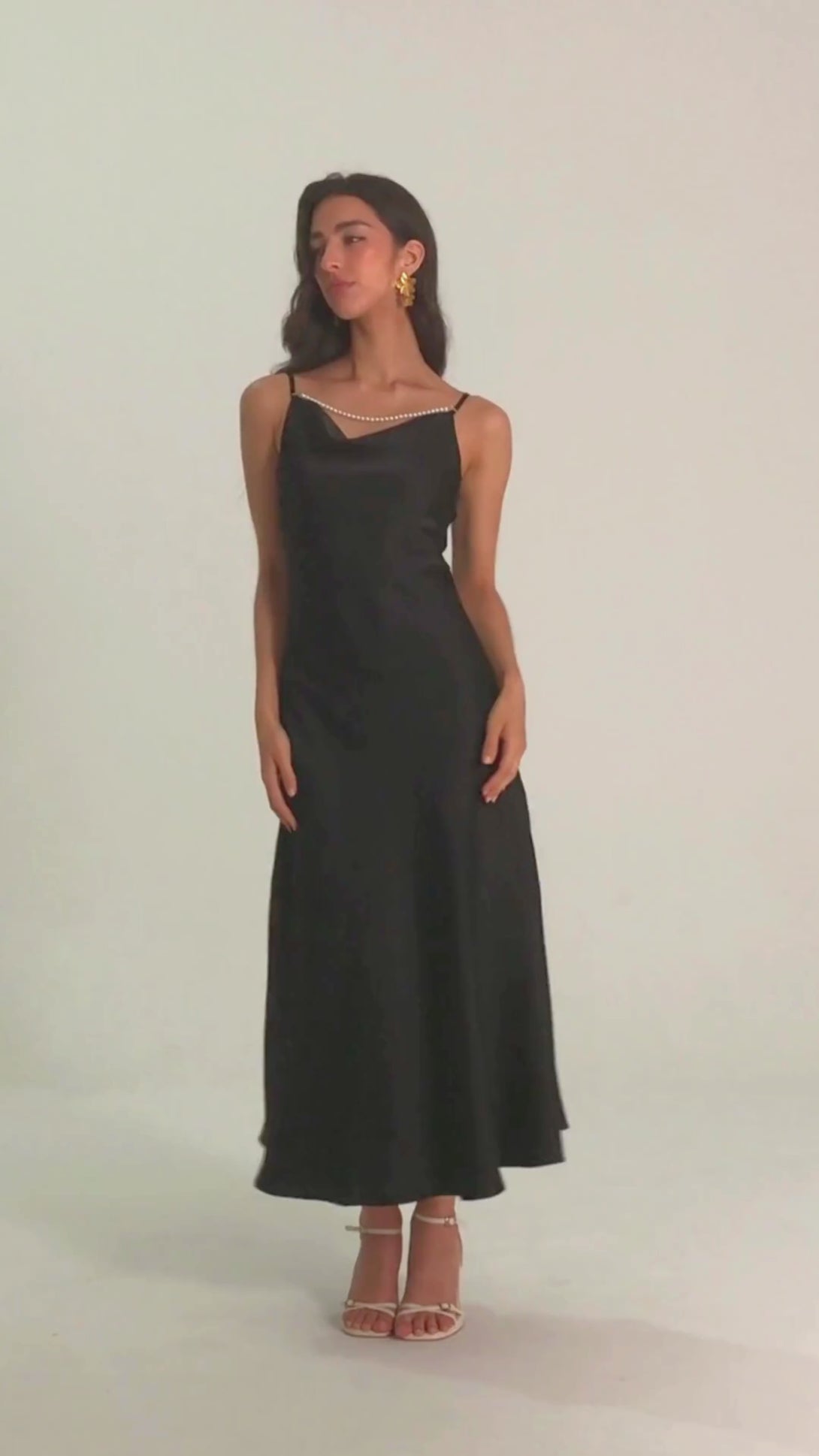 Woman wearing black satin maxi dress with pearl-trim neckline and spaghetti straps, front view