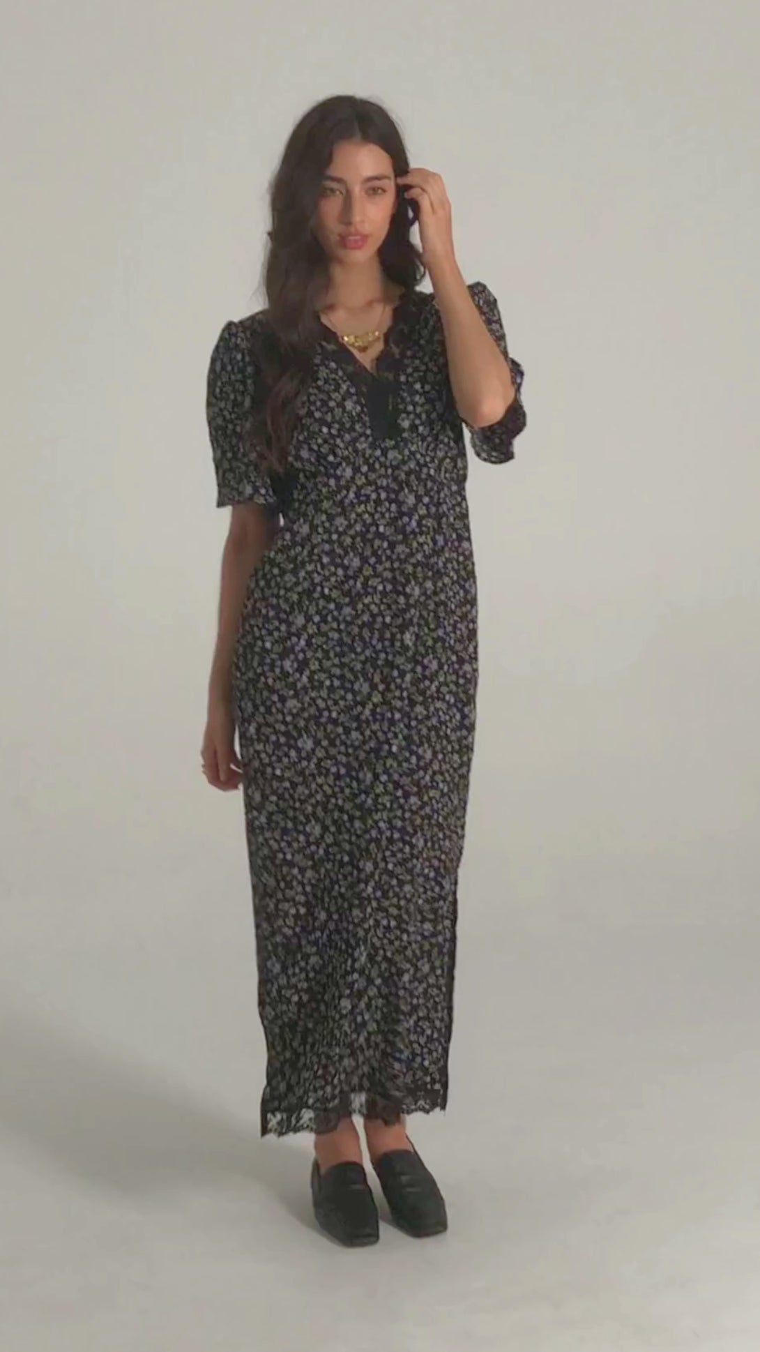 Model in a front-facing black midi dress with purple floral print, lace-trimmed neckline, short puff sleeves, and soft vintage silhouette.