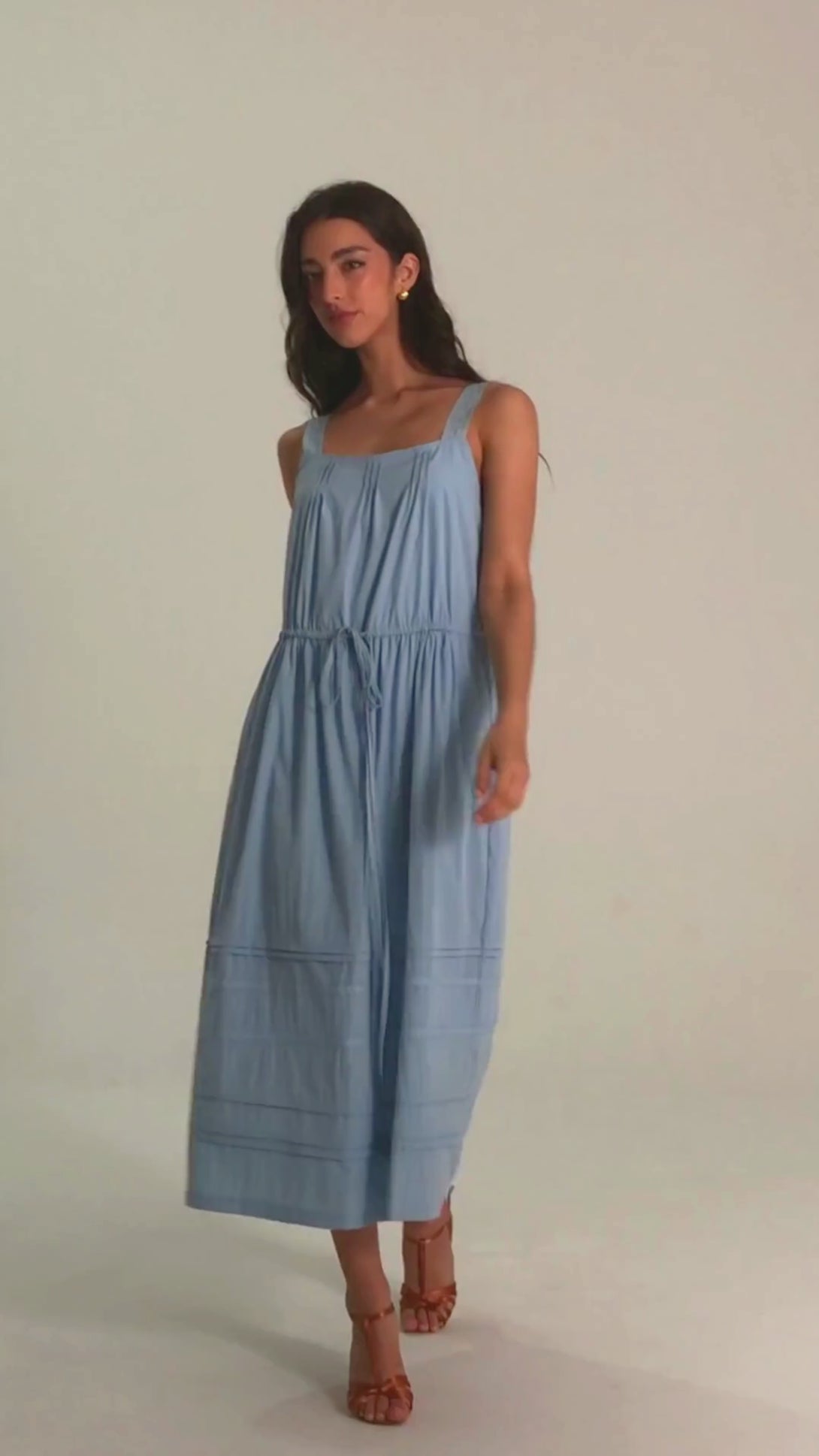 Front close-up of light blue sleeveless midi dress with square neckline, wide straps, pintuck skirt detail, and adjustable drawstring waist.