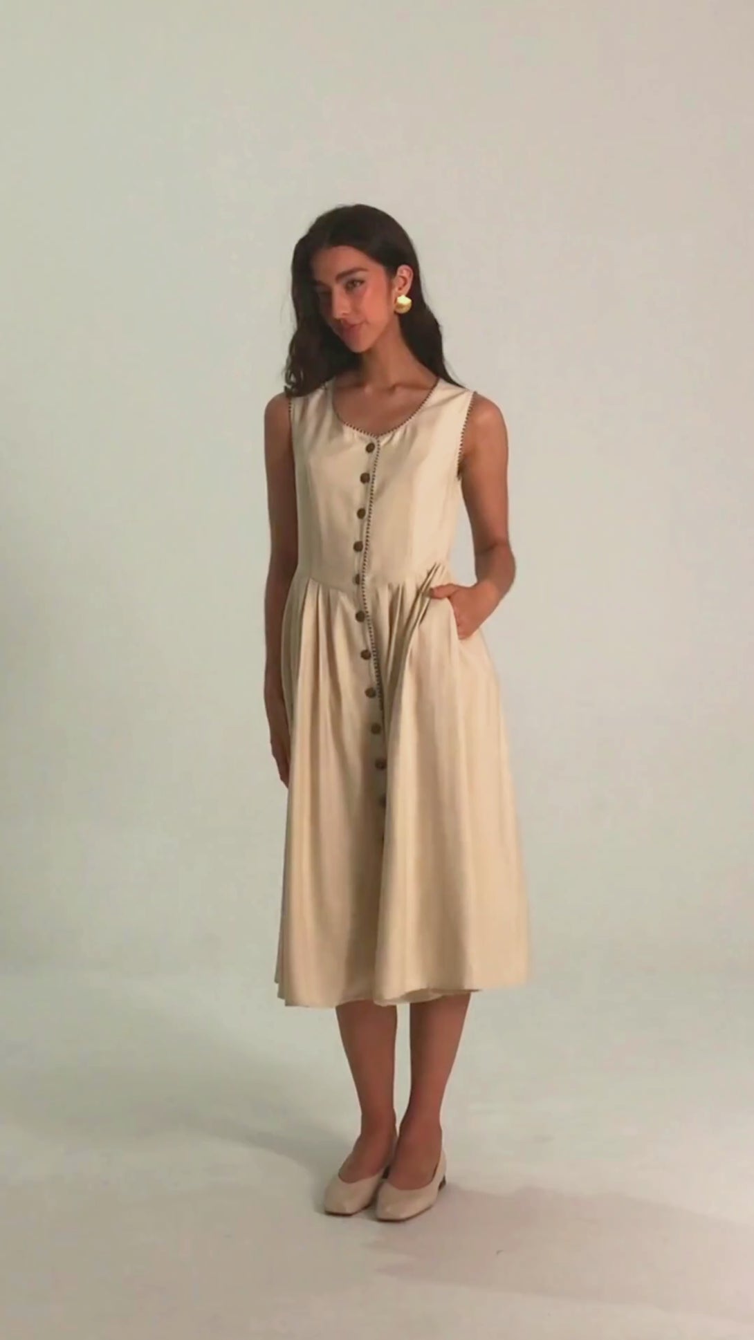 Front view of a women's white button-down midi dress with contrast black trim, pleated skirt, and sleeveless bodice.