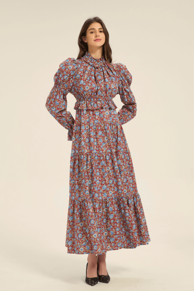 Front view of a red floral print maxi dress with puff shoulders, high neckline, and long sleeves, styled with black heels.