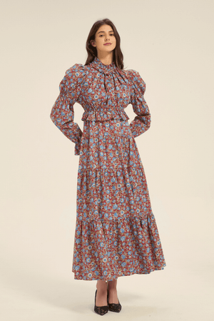 Front view of a red floral print maxi dress with puff shoulders, high neckline, and long sleeves, styled with black heels.