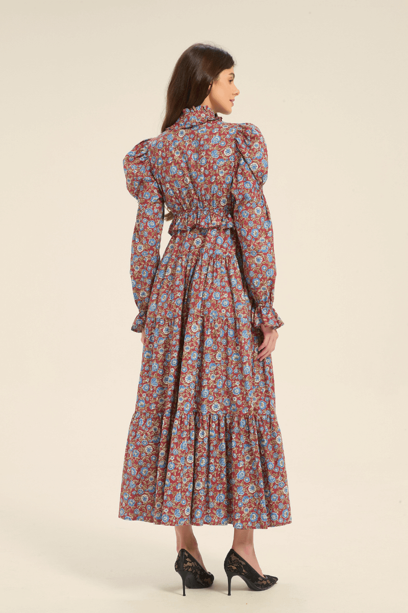 Back view of a red floral maxi dress with puff shoulders and tiered skirt, showing fitted waist and long sleeves.