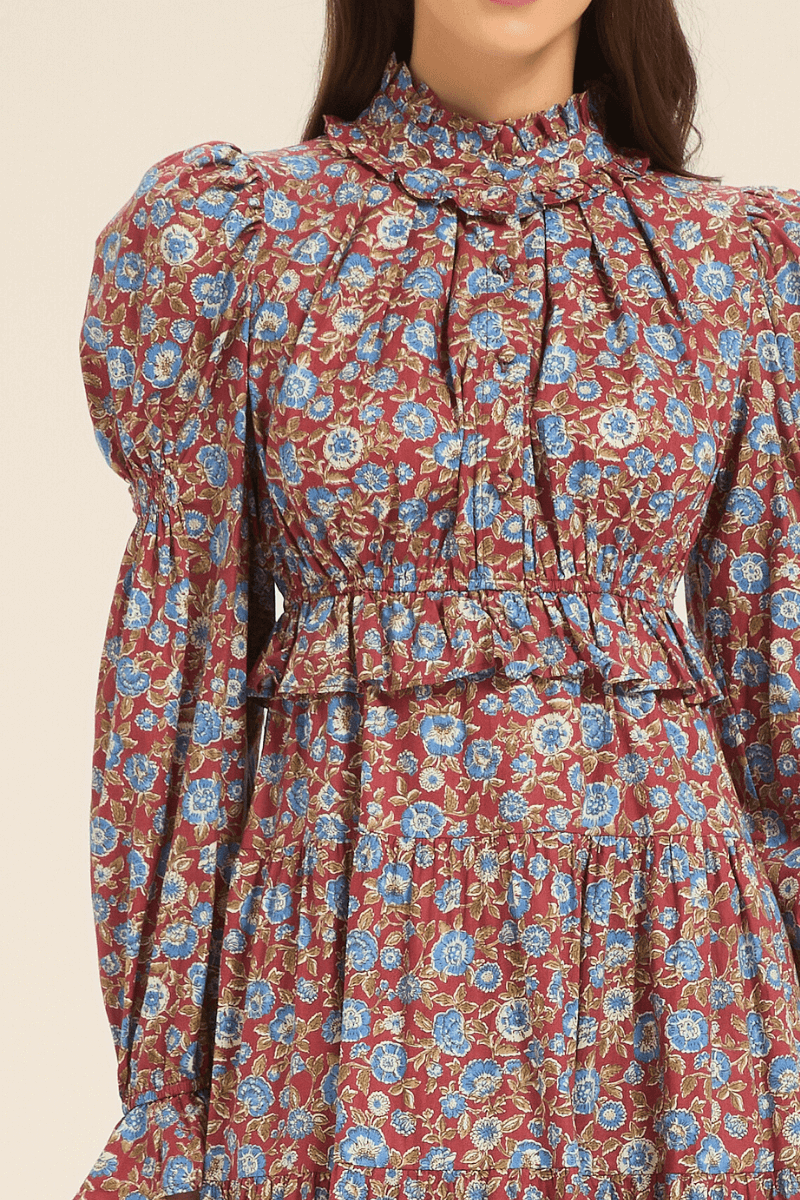 Close-up of the bodice on a red floral maxi dress, featuring ruffled high neck and blue flower print details.